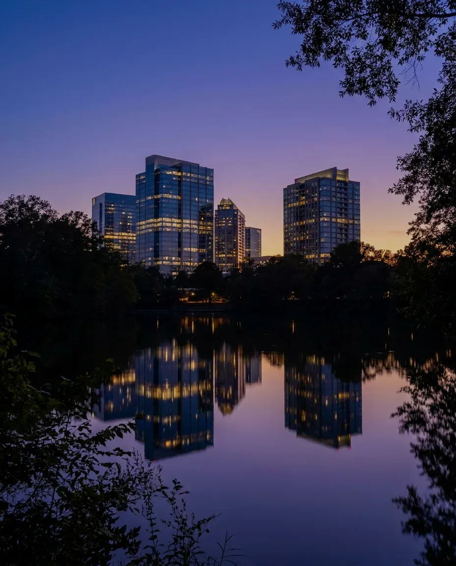 Office towers across a park lake at dusk.